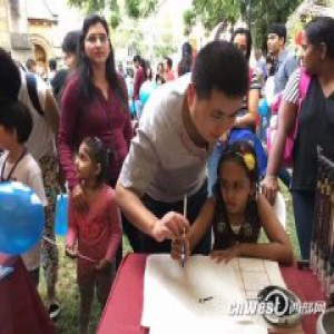 陕西的青年书画家陈震在庙会上手把手教当地儿童书写毛笔字。